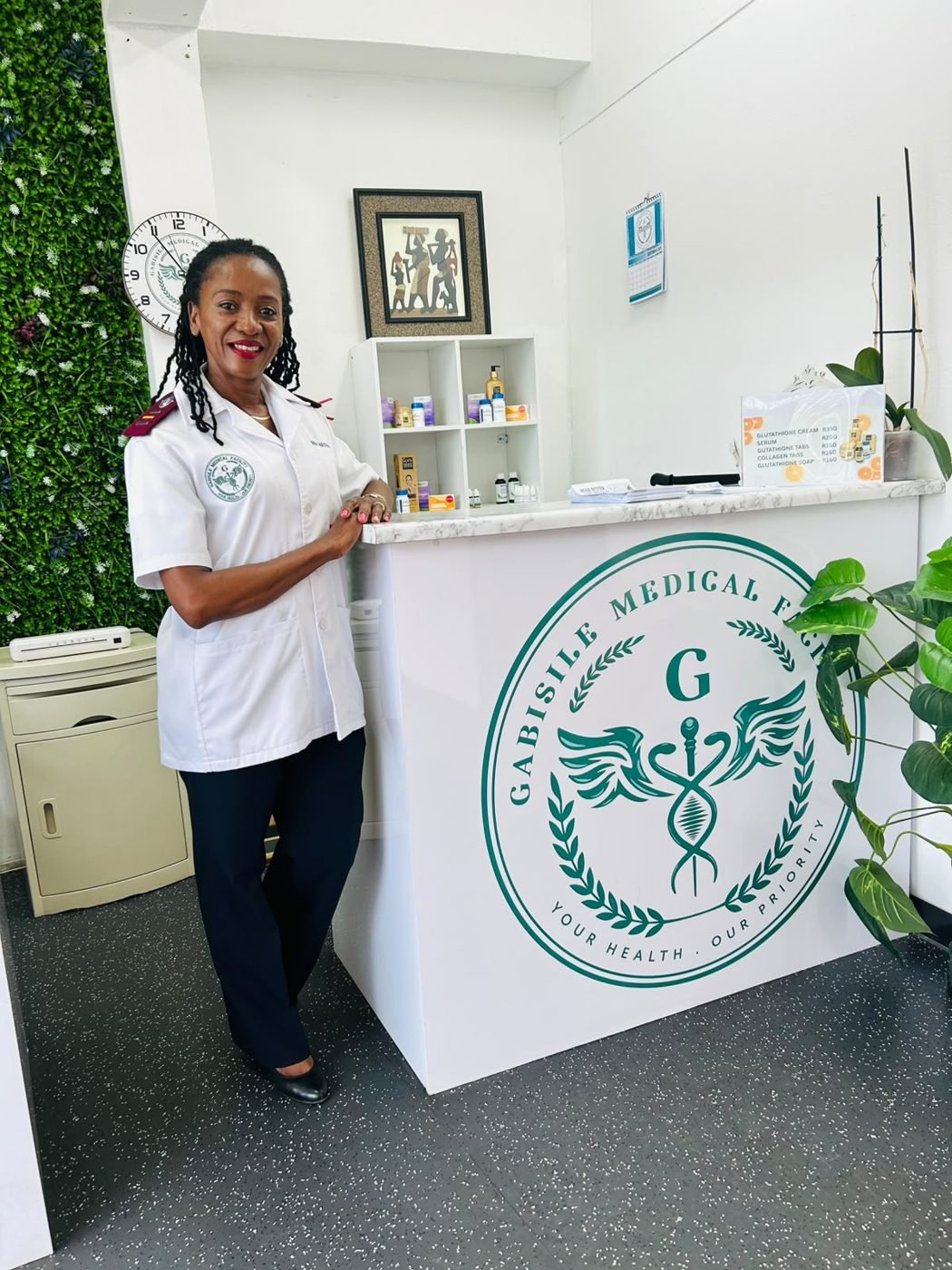 The clinic's private nurse practitioner standing at the Gabisile reception desk, smiling