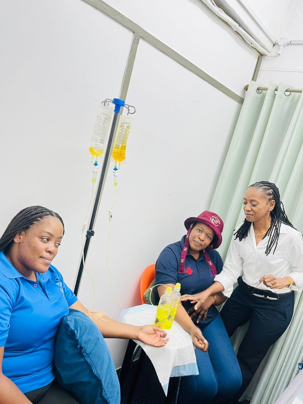 Two patients relaxing during IV drips while the nurse checks on them